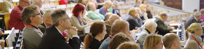Mehrer Personen in einem Hörsaal lauschen gespannt einem Vortrag.