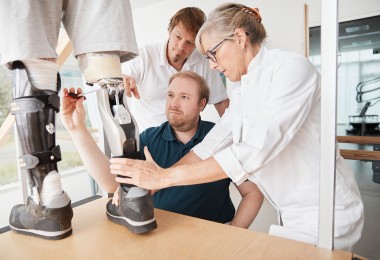 Ärztliches Personal passt bei einem Patienten eine Prothese des Unterschenkels an.